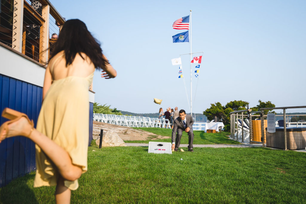 Couple at wedding reception playing corn hole outside.