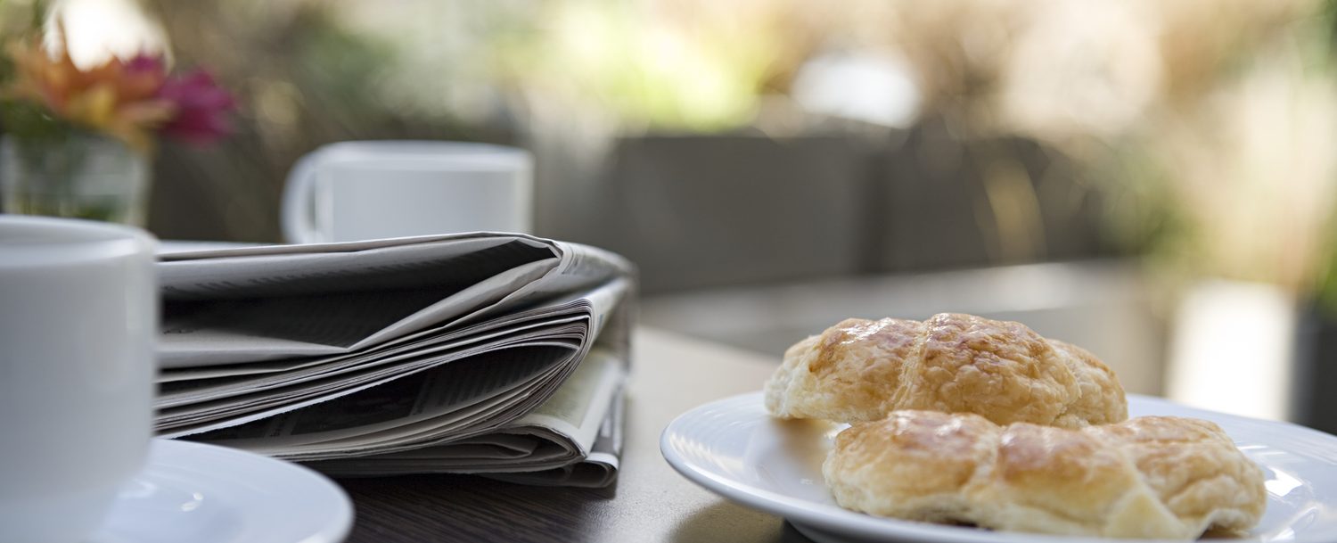 Close up of breakfast Danish, newspaper and coffee.