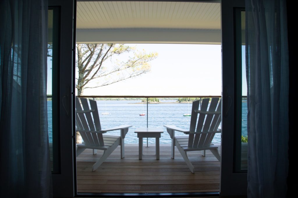 White patio furniture on lodge room deck looking out to bay.