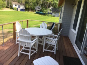 White patio furniture on wooden deck.