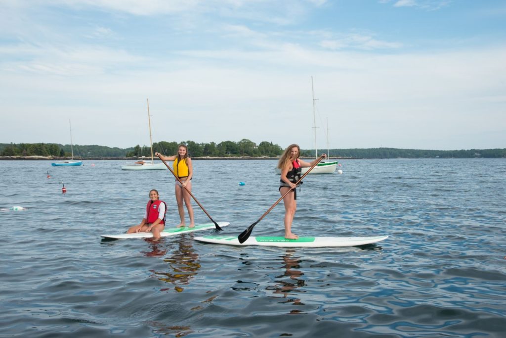 Three young women on stand up paddleboards on Linekin Bay