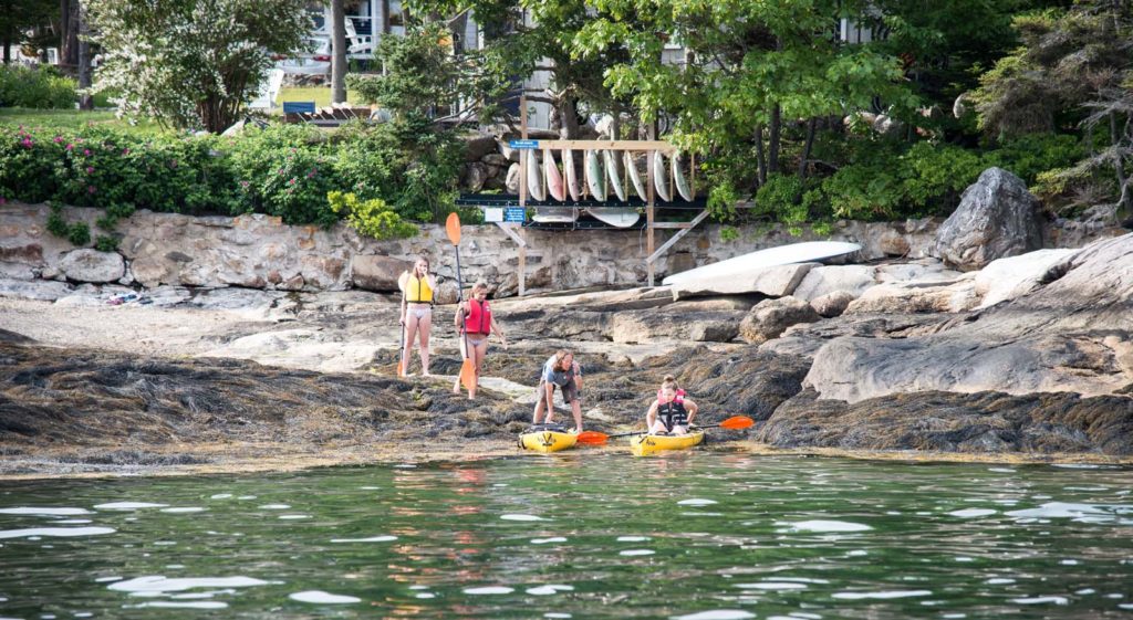 People getting in kayaks on the shore.