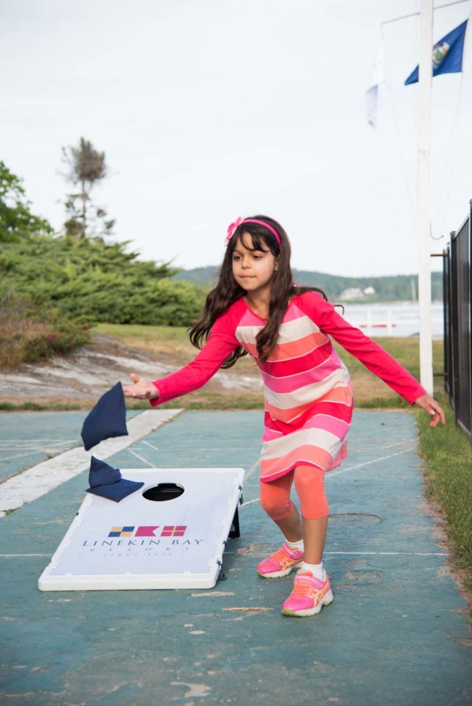 Young girl throwing a corn hole bag.